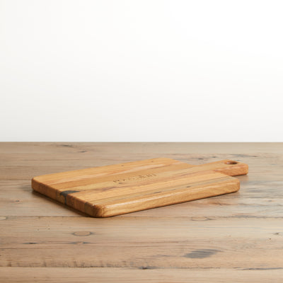 Reclaimed Oak rectangle cutting board with handle. Natural oak color with grain. Laying flat on table