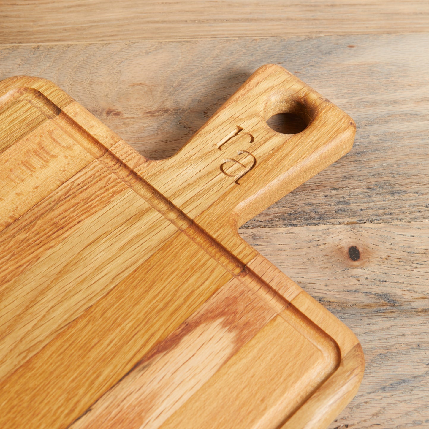 Reclaimed Oak cutting board with natural color. RA carved into handle.