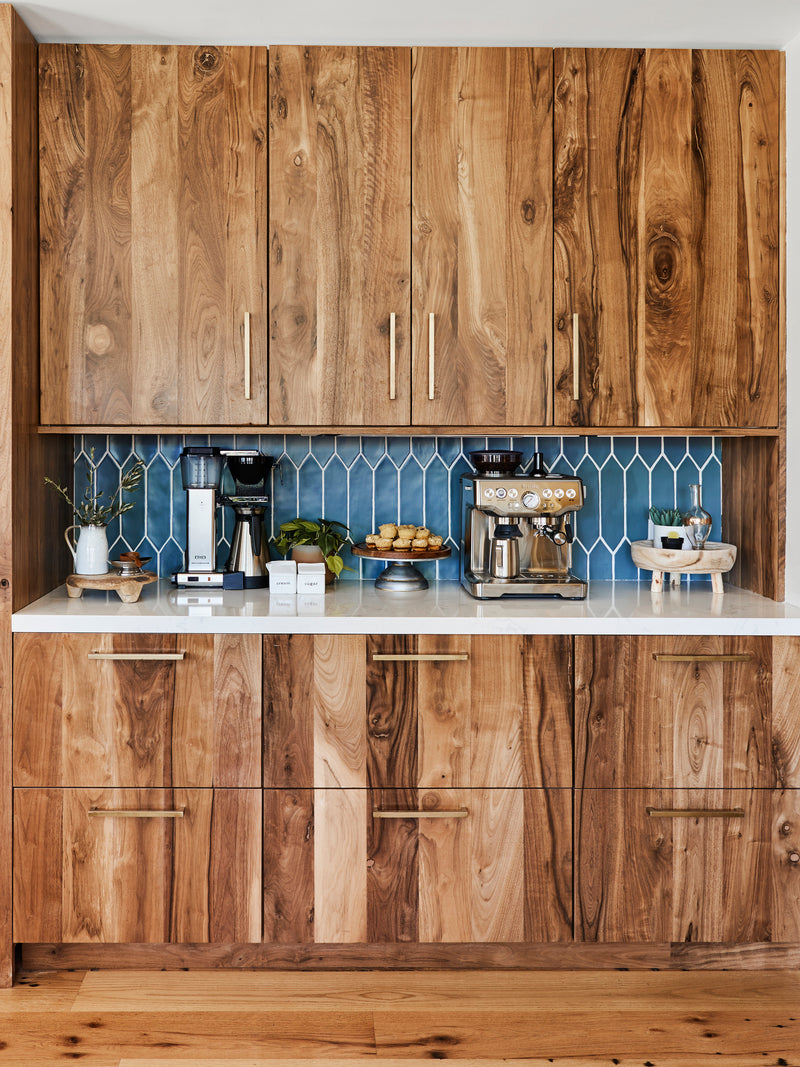 Walnut upper cabinets and lower drawers. Natural wood grain. Blue tile backsplash.